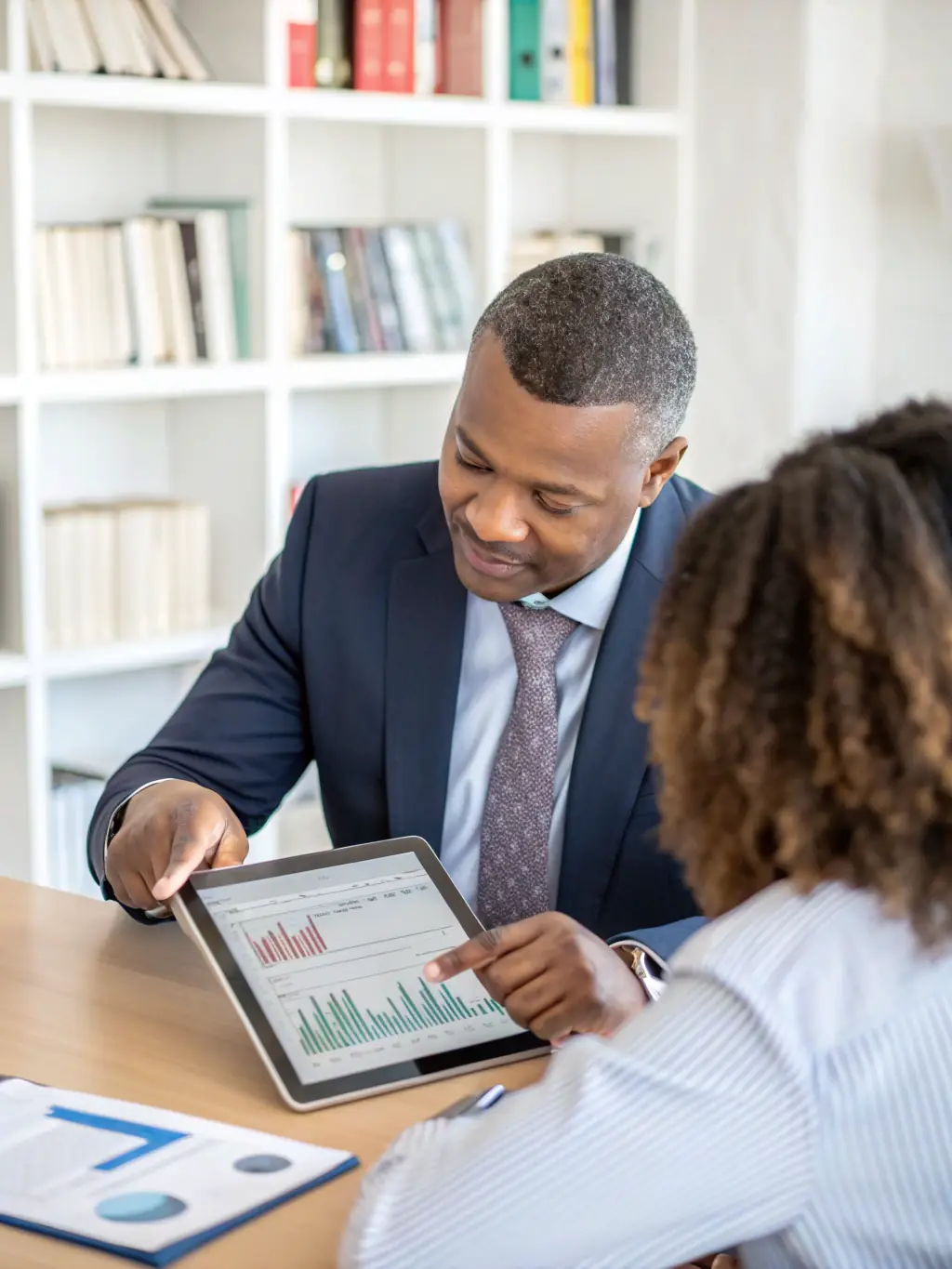 A South African entrepreneur reviewing financial reports with a consultant, showcasing support for small business investment.